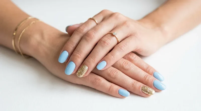 Hands with baby blue nail polish and gold glitter accent nails in a professional beauty photography style